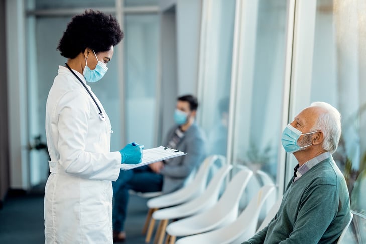 African-American-doctor-analyzing-medical-report-of-her-senior-patient-at-medical-clinic.